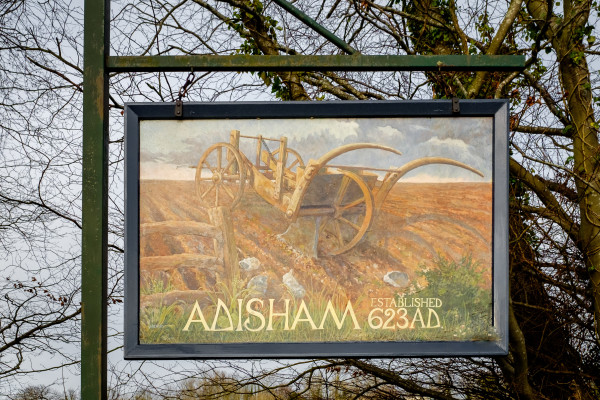 Wooden sign with the text Adisham established 623 AD